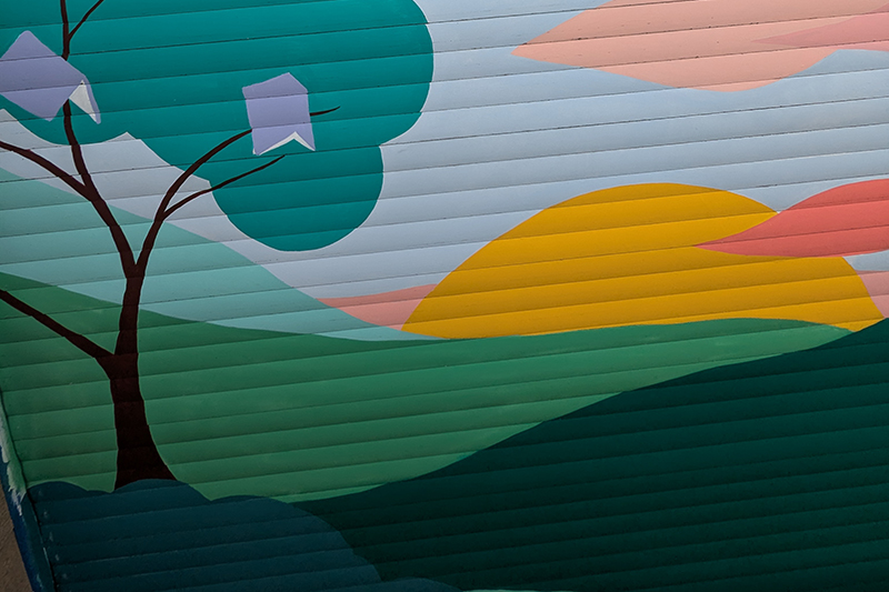 Large street art mural of trees and hills