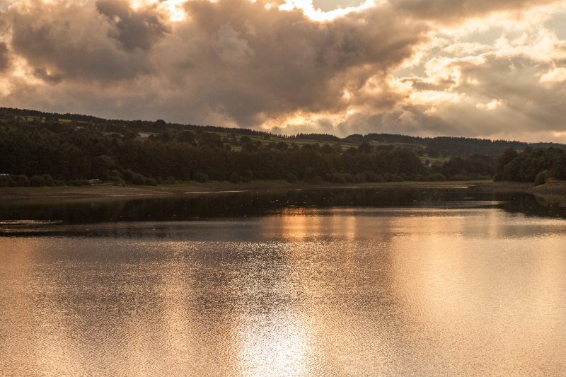 A lake with sun shining through the clouds
